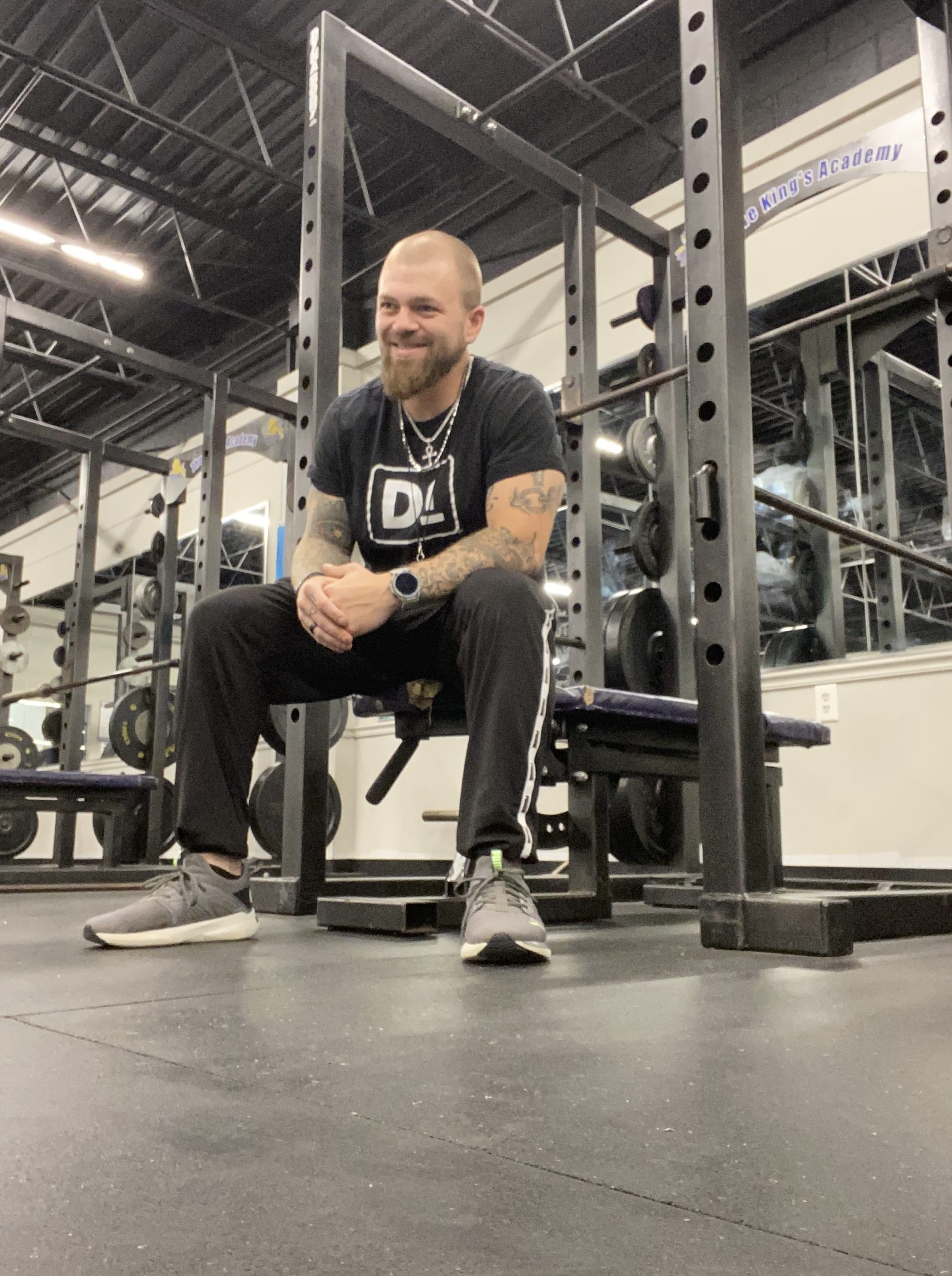 Adam Kerr sitting on a weight bench smiling in fitness attire
