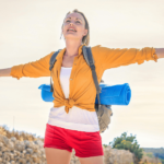 Girl with arms out to either side smiling while hiking.