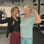 two women showing strength in a gym