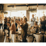 people clapping and standing next to their tables at a nice event