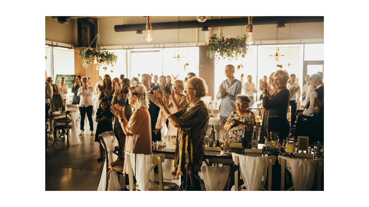 people clapping and standing next to their tables at a nice event