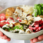 hands holding a tofu vegetable rice bowl