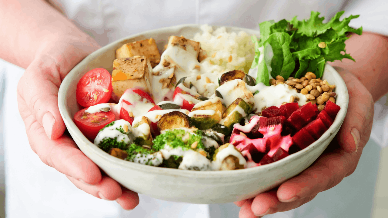 hands holding a tofu vegetable rice bowl
